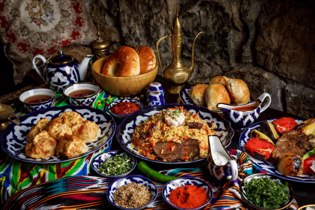 An Uzbek table set with plov, somsa, bread, and tea